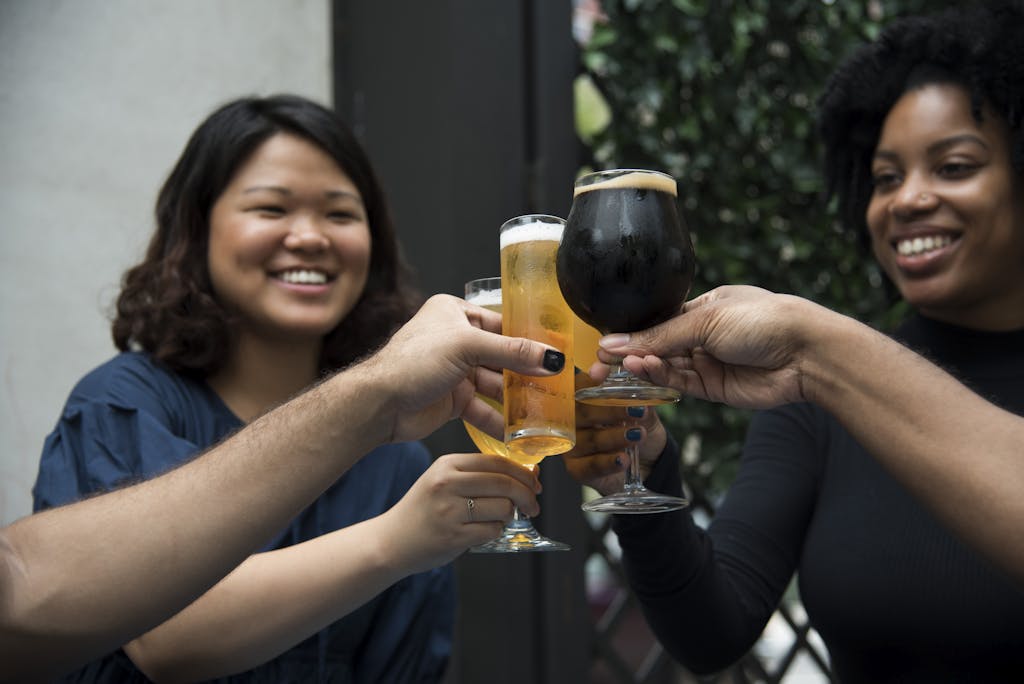 A joyful group of friends toasting with beer, symbolizing celebration and friendship in an outdoor setting.